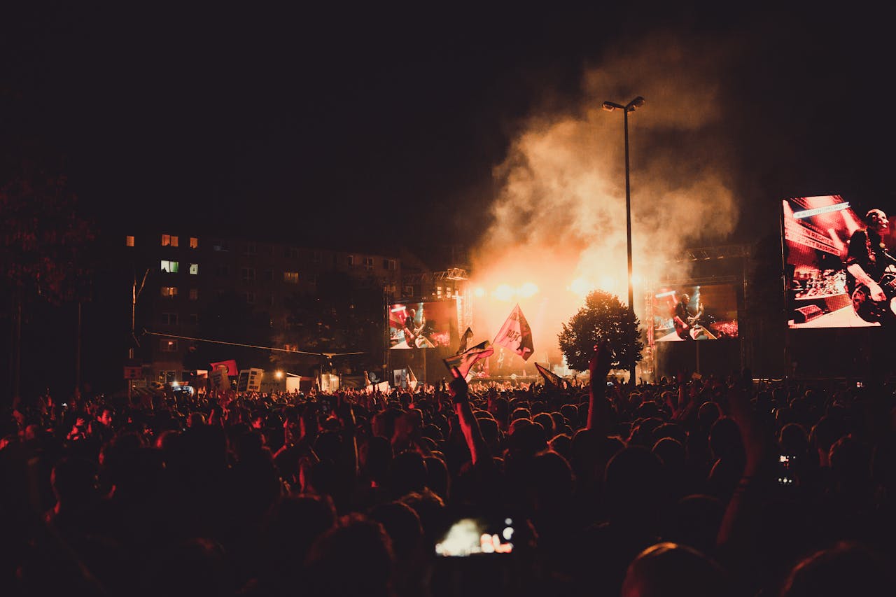 A dynamic live music concert with a large crowd, stage lights, and performer spotlight.